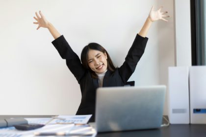 A business woman who is happy and excited when she hears the news gets a bonus.