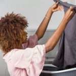 Young black African American woman washing her clothes in a auto