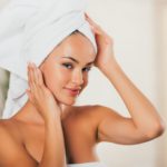 young smiling woman correcting towel on head at spa salon