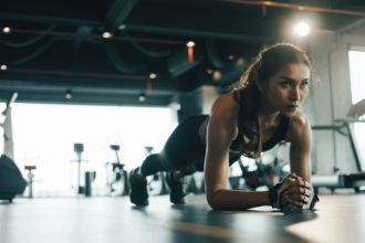 Young woman doing plank exercise while exercising in gym.